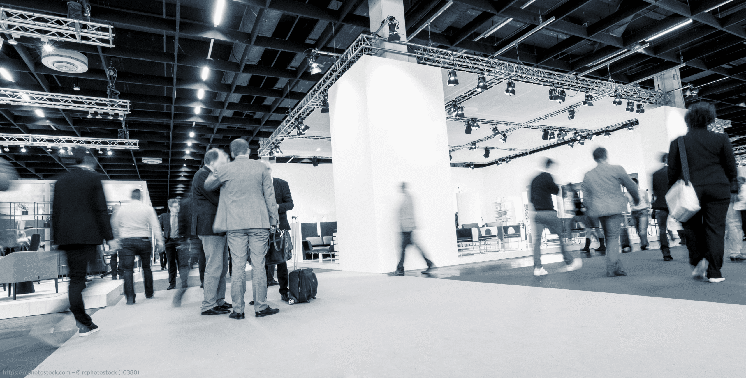 black and white image of people walking around a tradeshow