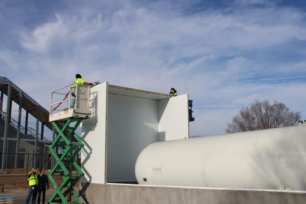 Crew works on installing a slab mounted enclosure
